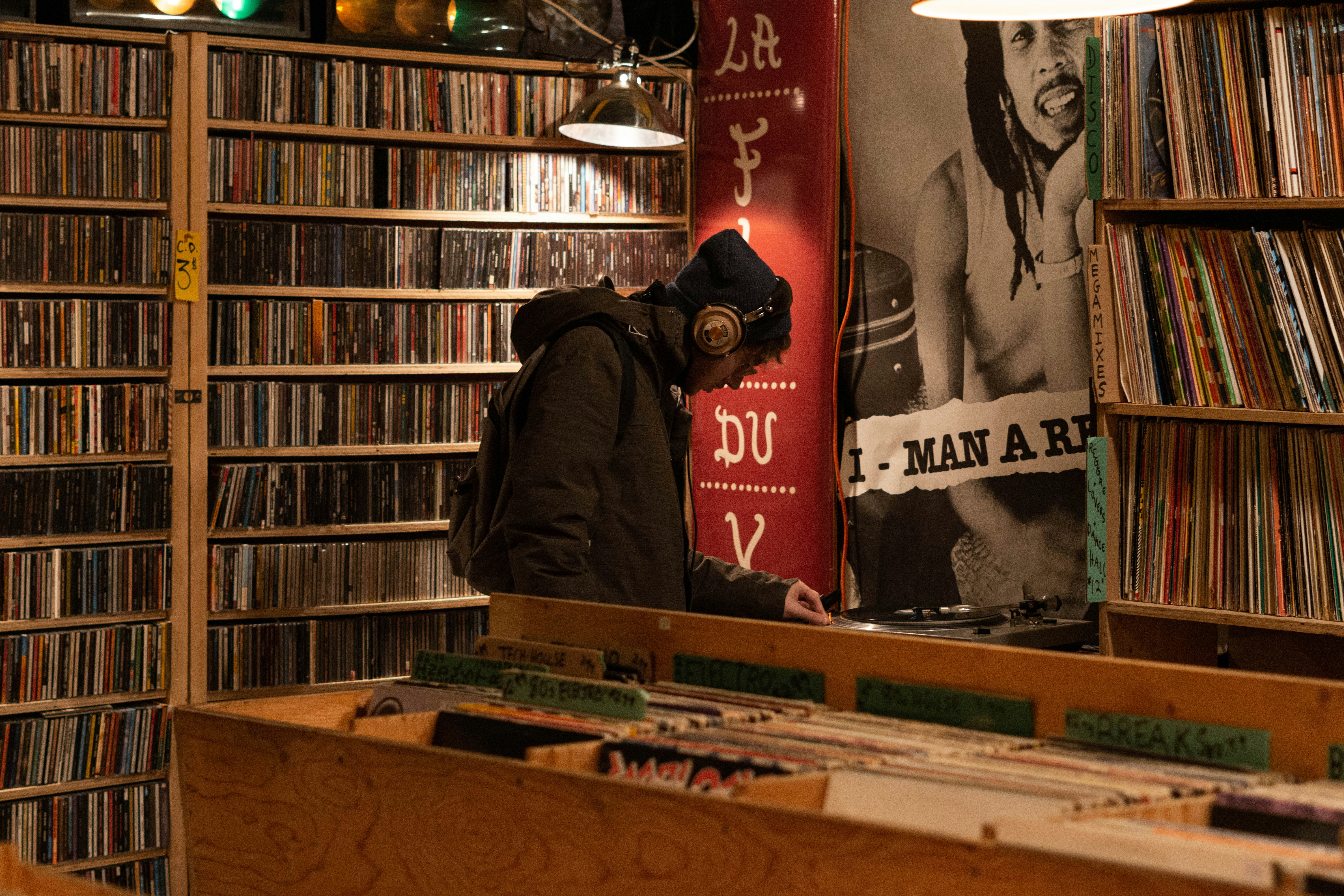 man in hoodie and headphones standing inside record store